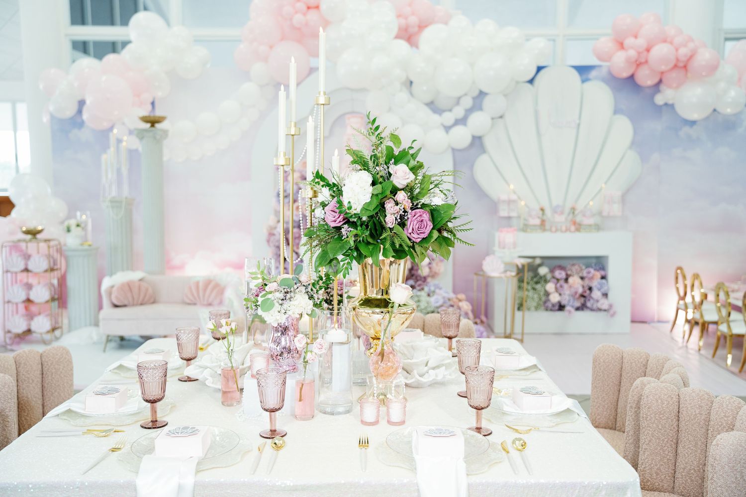 Elegant pink and white party decor with floral arrangements and table settings in a dreamy pastel color scheme.