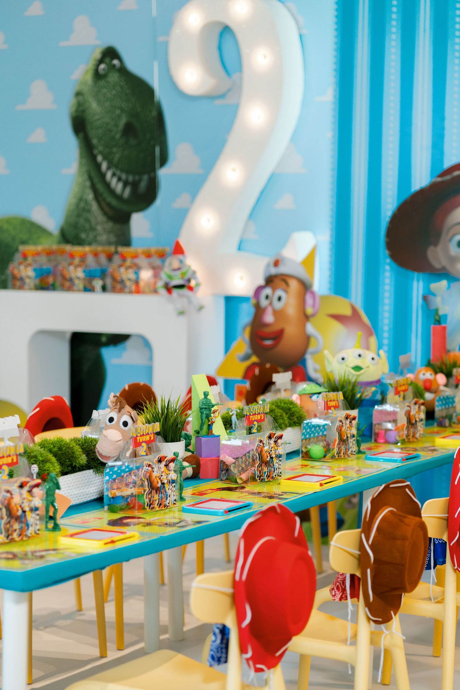 Long party table decorated with Toy Story characters and blue sky themed backdrop.