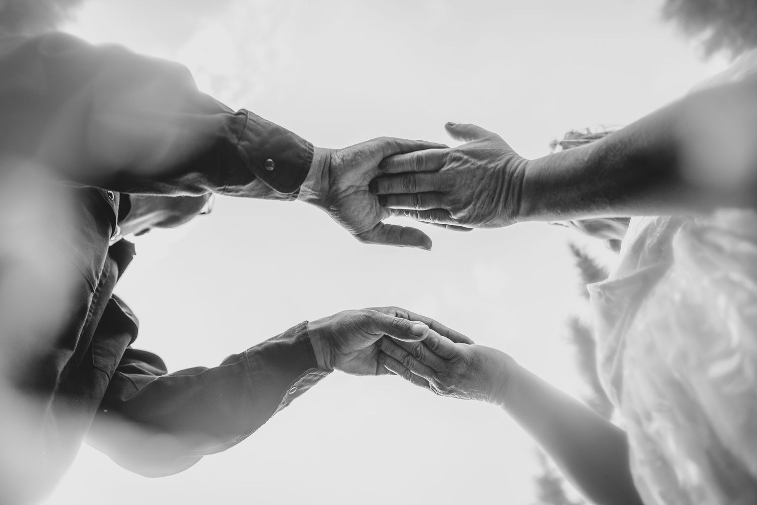 Black and white photo of multiple hands reaching toward each other in a gesture of connection and unity.