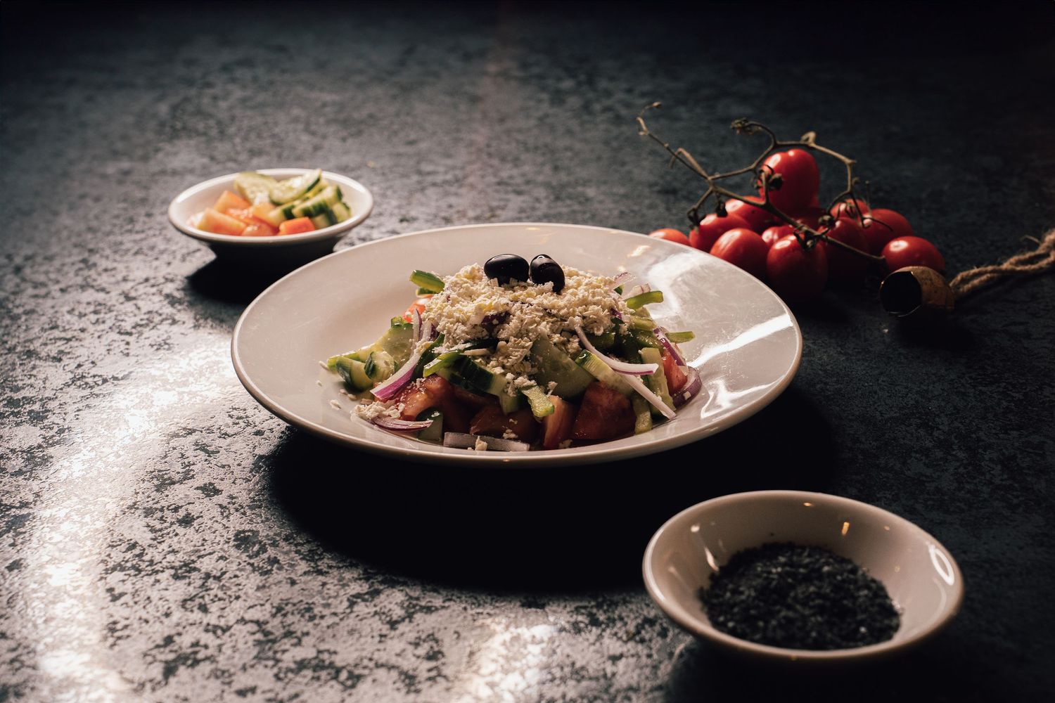 Elegant restaurant salad with quinoa, fresh vegetables, olives, and cherry tomatoes on marble table.