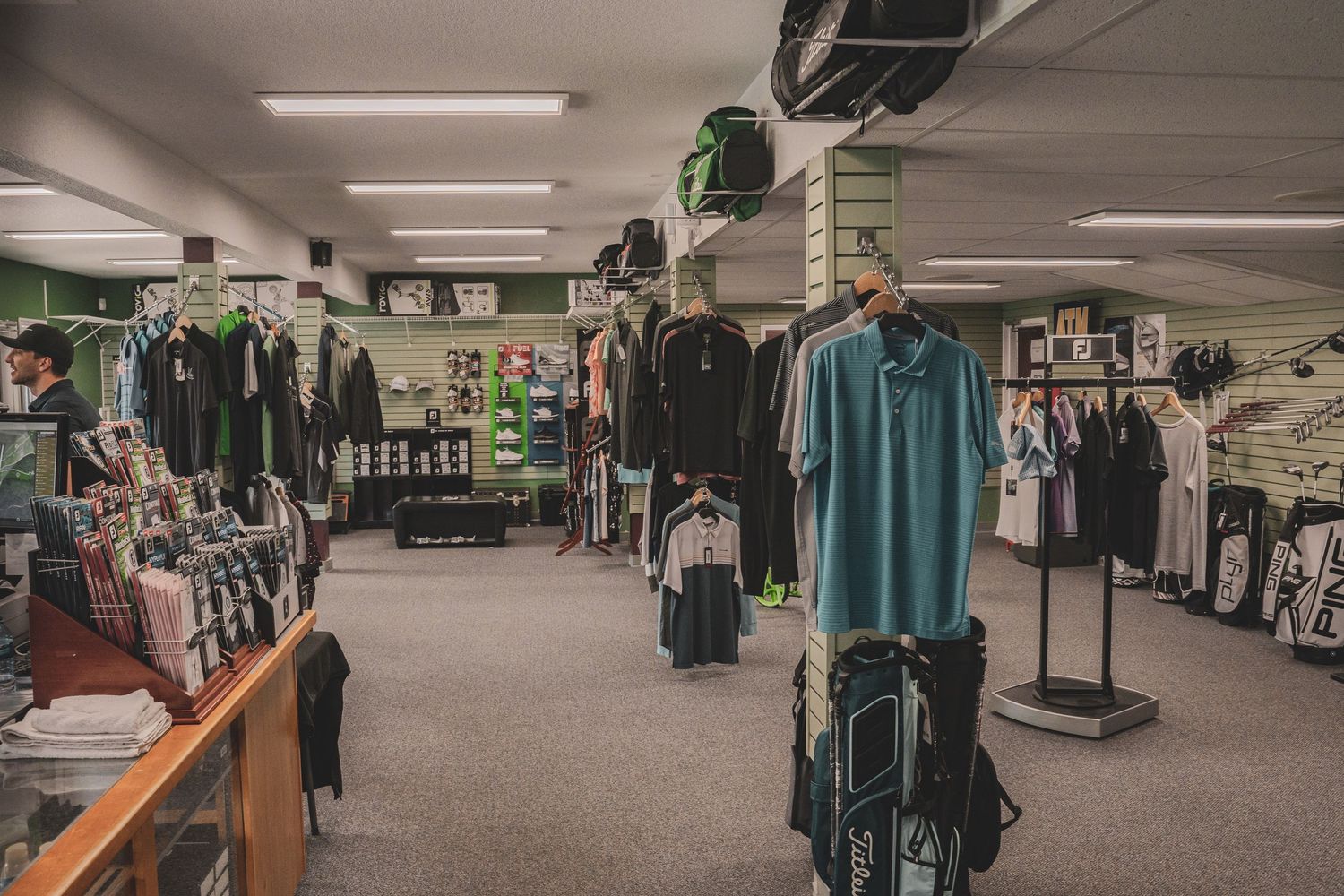 Interior of a golf pro shop displaying clothing, equipment, and accessories on racks and shelves.