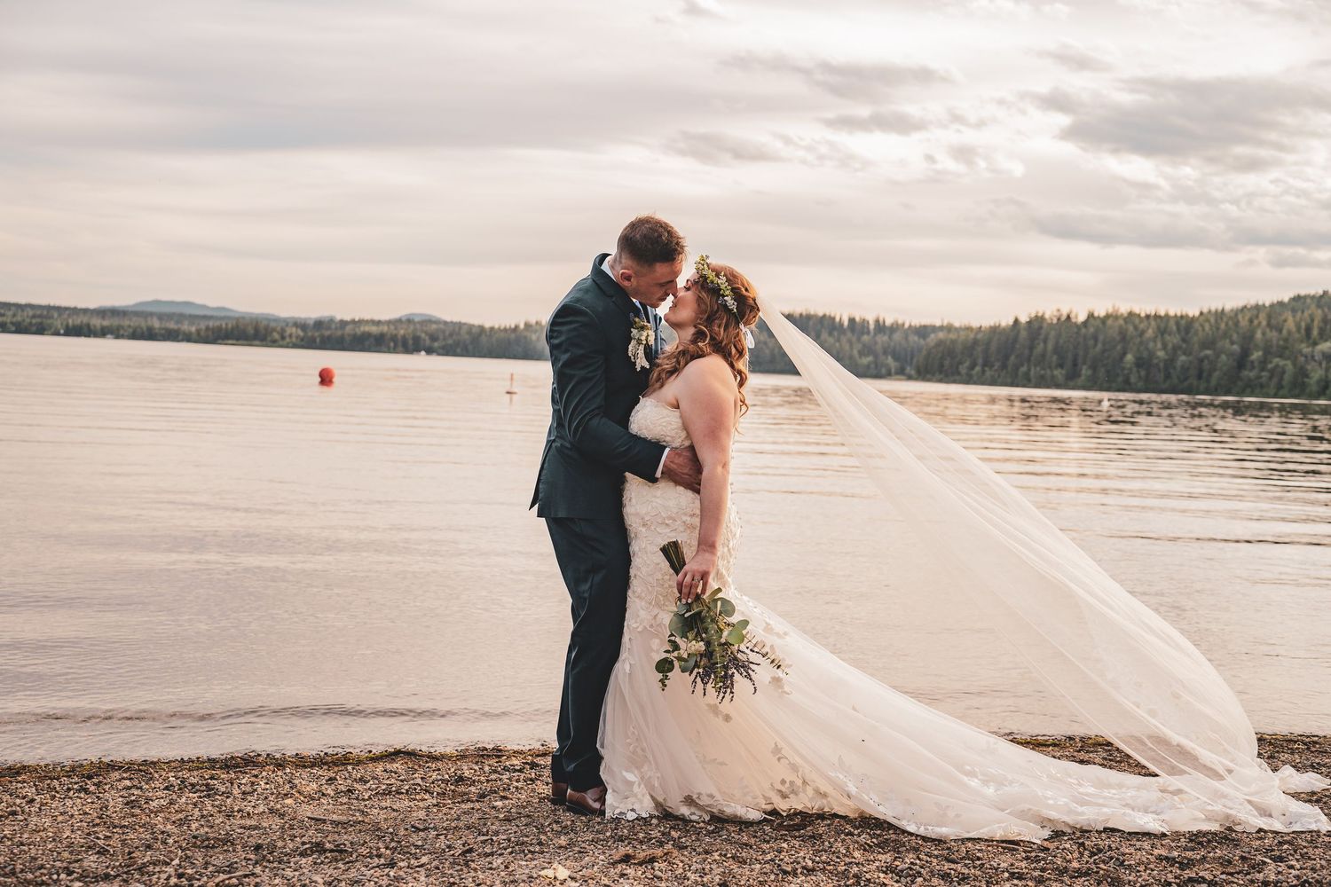 Bride and groom share a romantic kiss by West Lake, serene lake shore, with the wedding veil flowing in the breeze. Elopement options in PG.