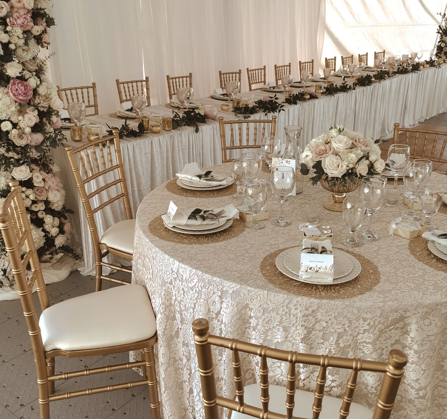 Elegant wedding reception setup with gold Chiavari chairs, lace tablecloths, and floral centerpieces.