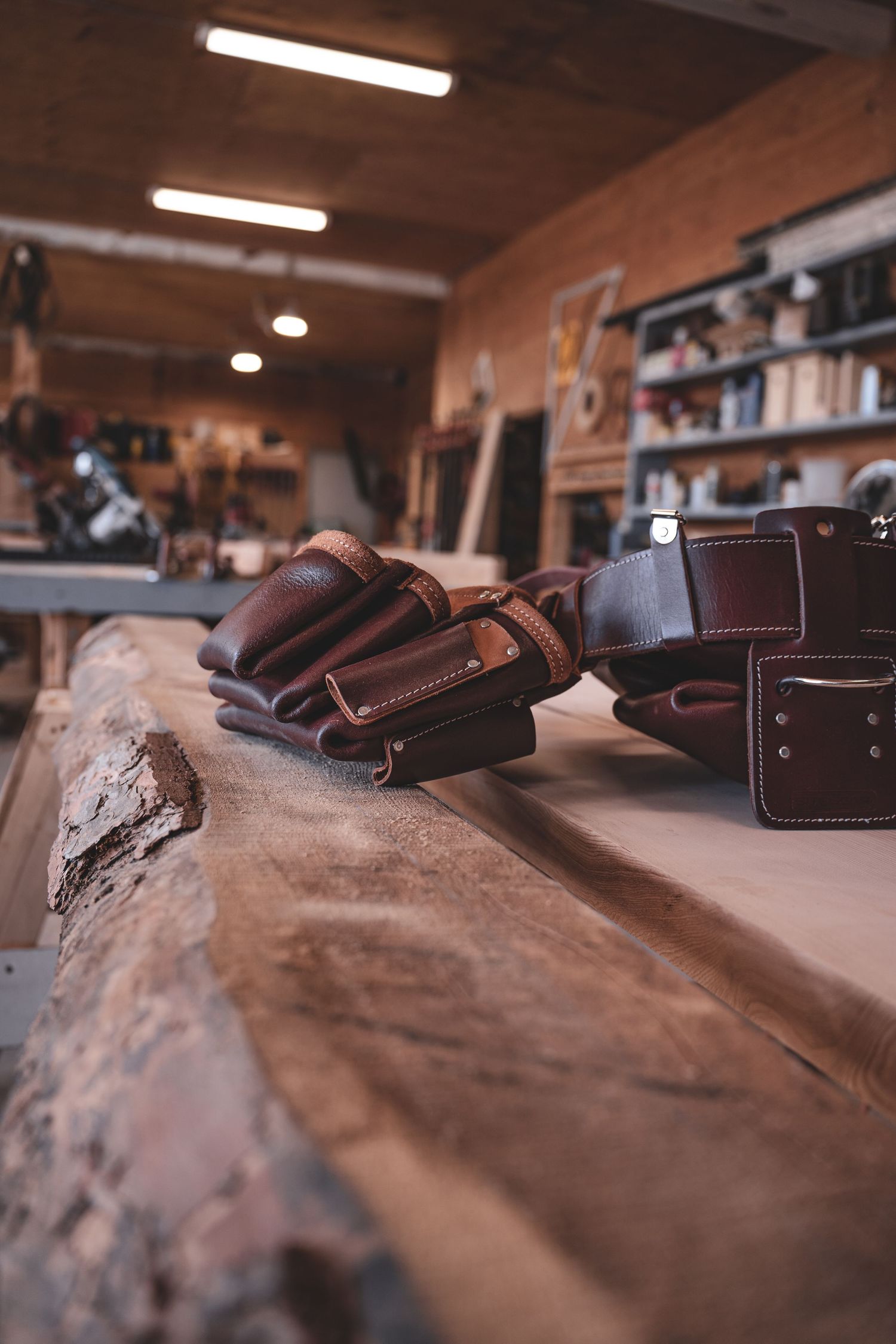 Brown leather work gloves resting on rustic wood plank in carpentry workshop.