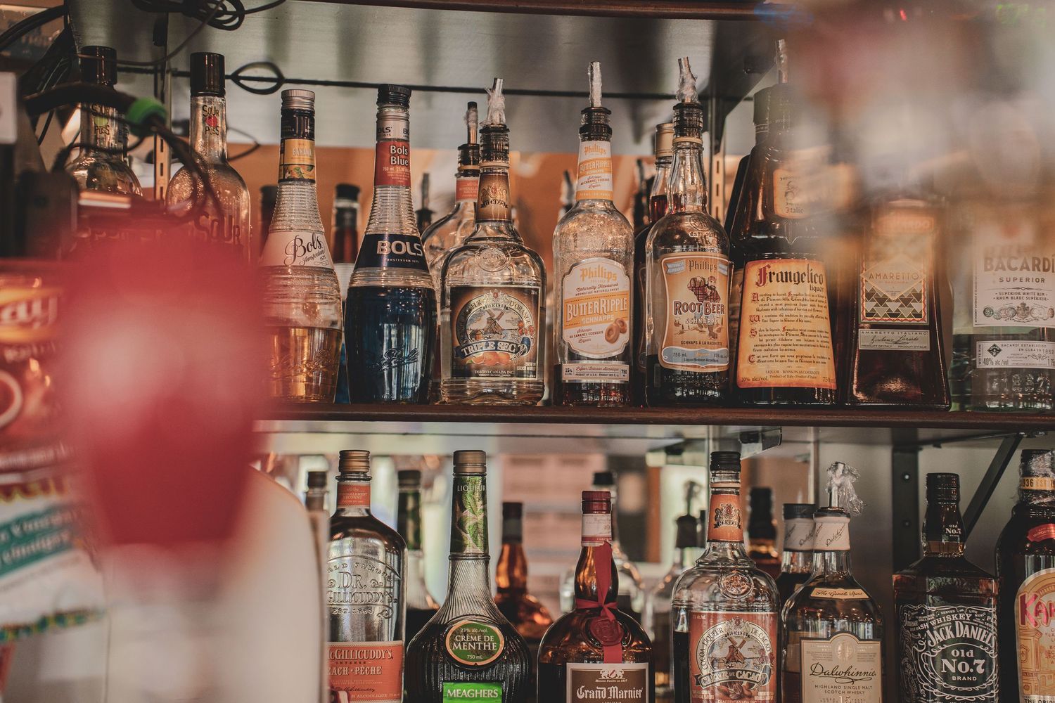 Rows of assorted liquor bottles on backlit shelves in a well-stocked bar.