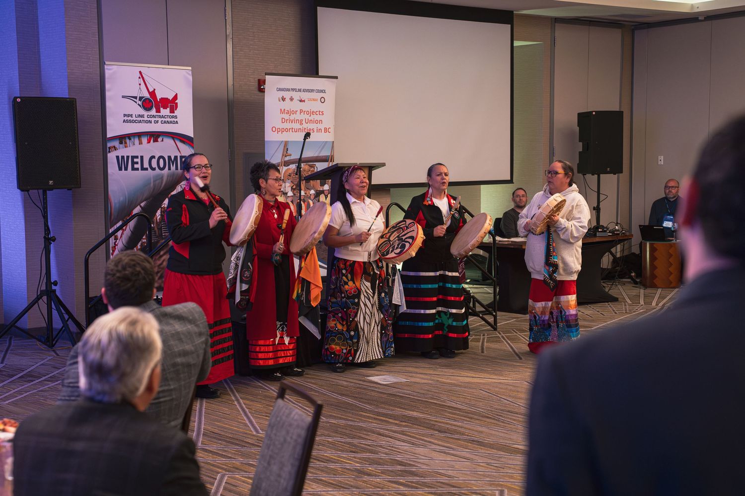 Indigenous performers in traditional regalia perform a cultural dance at a welcome ceremony during a professional conference event.
