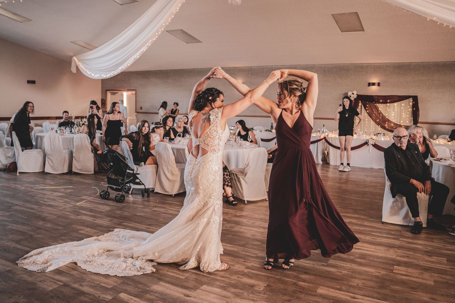 Bride and bridesmaid share a joyful dance together on the wedding reception dance floor at Blackburn Hall, wedding venue.