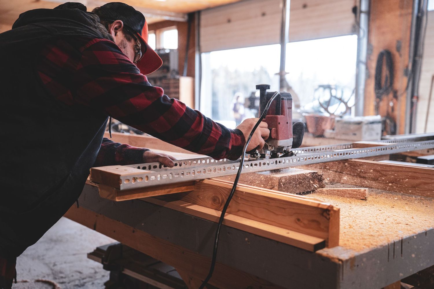 Worker using power tool on lumber in a rustic woodworking shop during winter during Commercial Business Branding photoshoot.