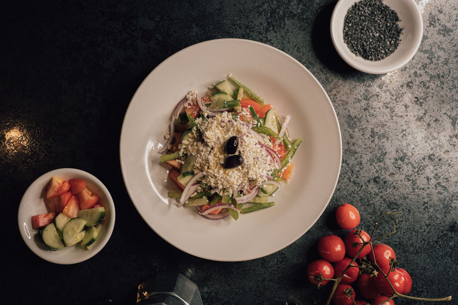 Overhead view of fresh vegetable salad with seeds on dark marble surface.