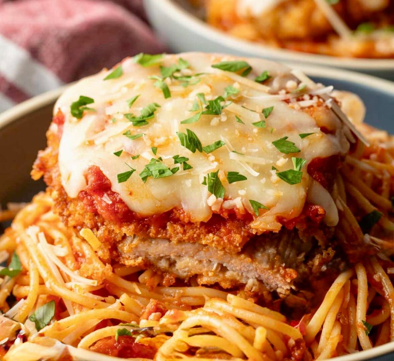 Chicken parmesan topped with melted cheese and marinara sauce product photo, served over spaghetti pasta, offered at Ulysses Restaurant.