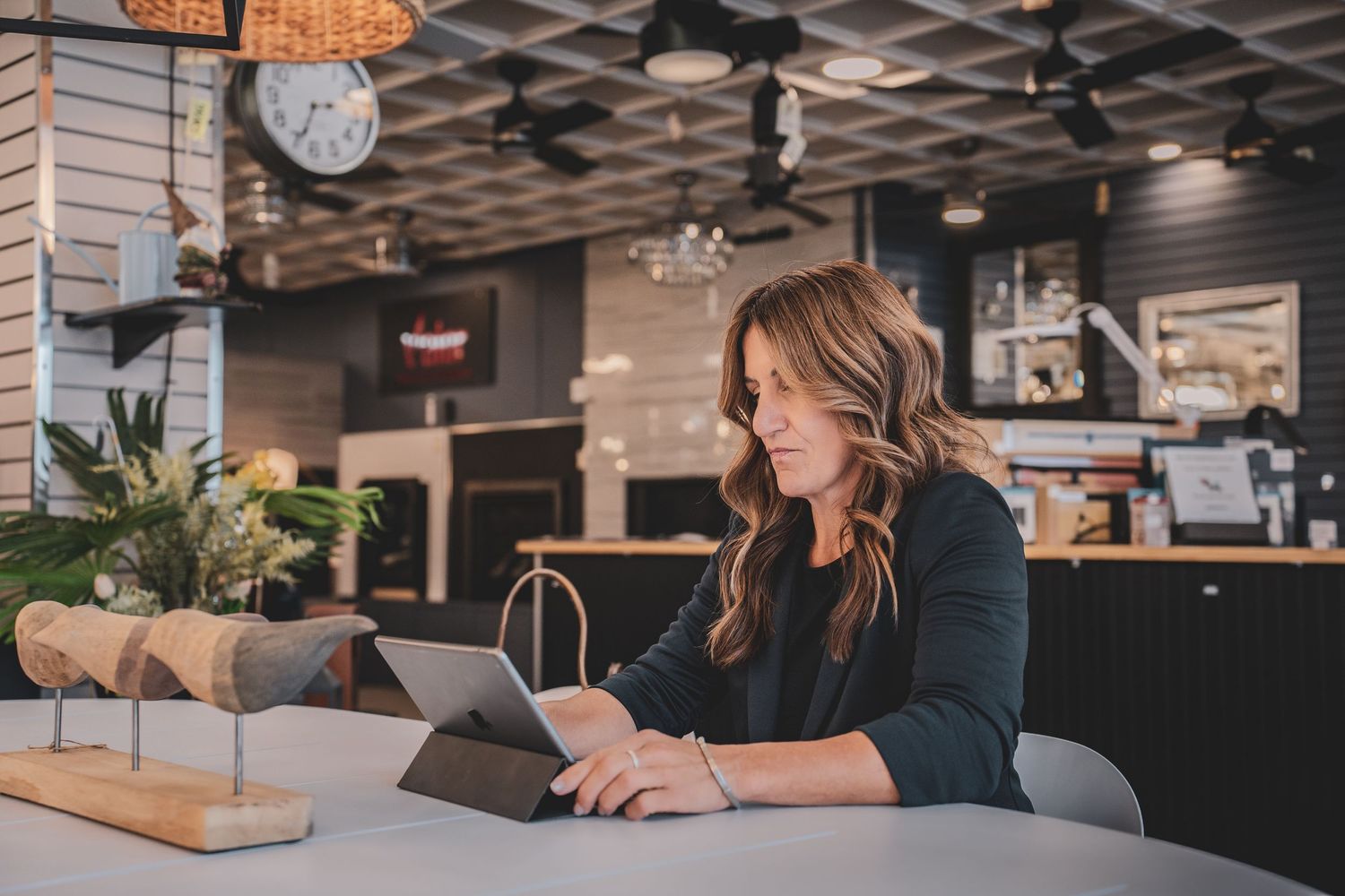 Professional woman using a tablet at a modern restaurant or showroom counter.