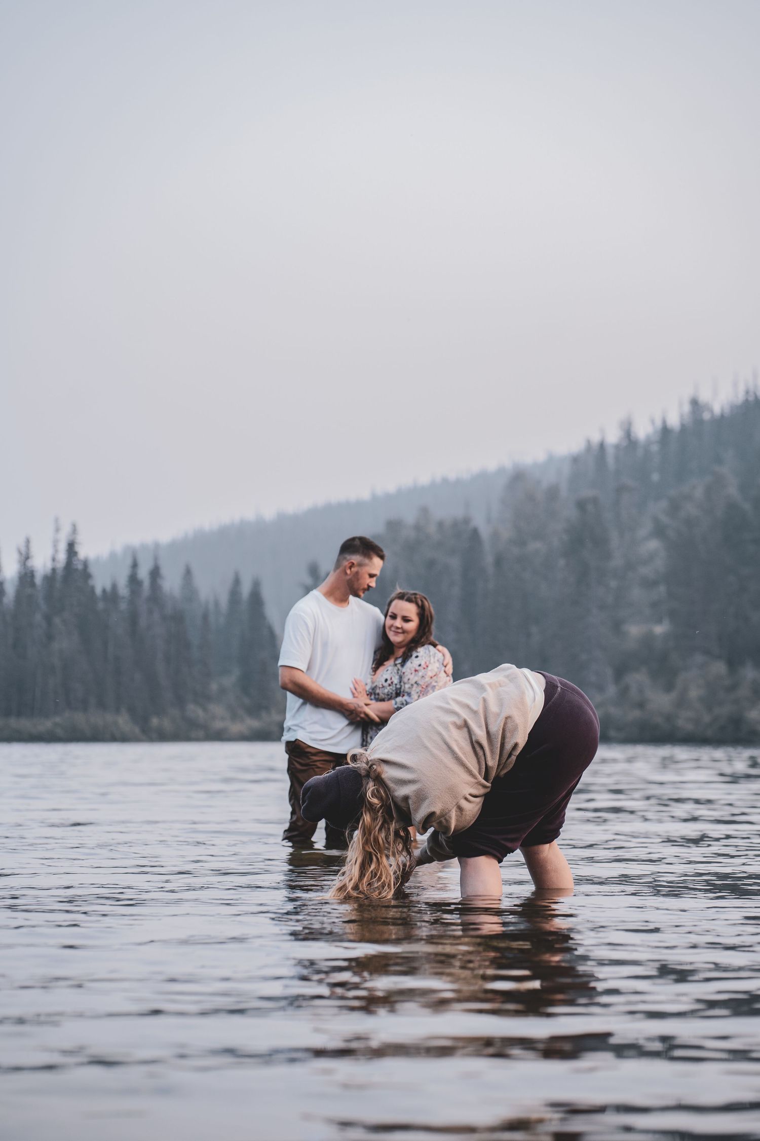 Couple standing in a mountain lake during an outdoor engagement ceremony with mountain, lake in Northern BC Canada.
