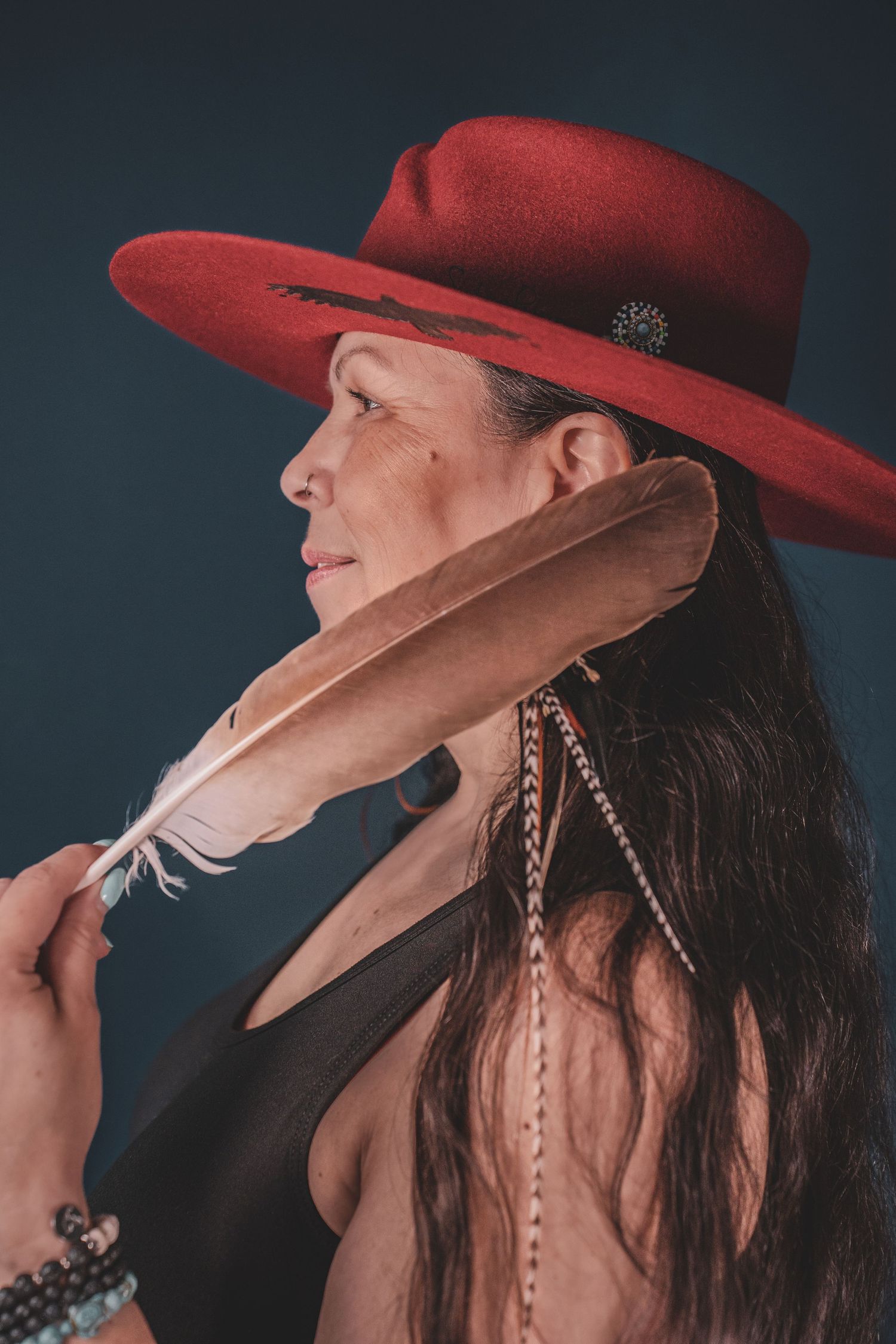 Kym Gouchie, wearing beaded earrings, profile view against dark background during musician photoshoot.