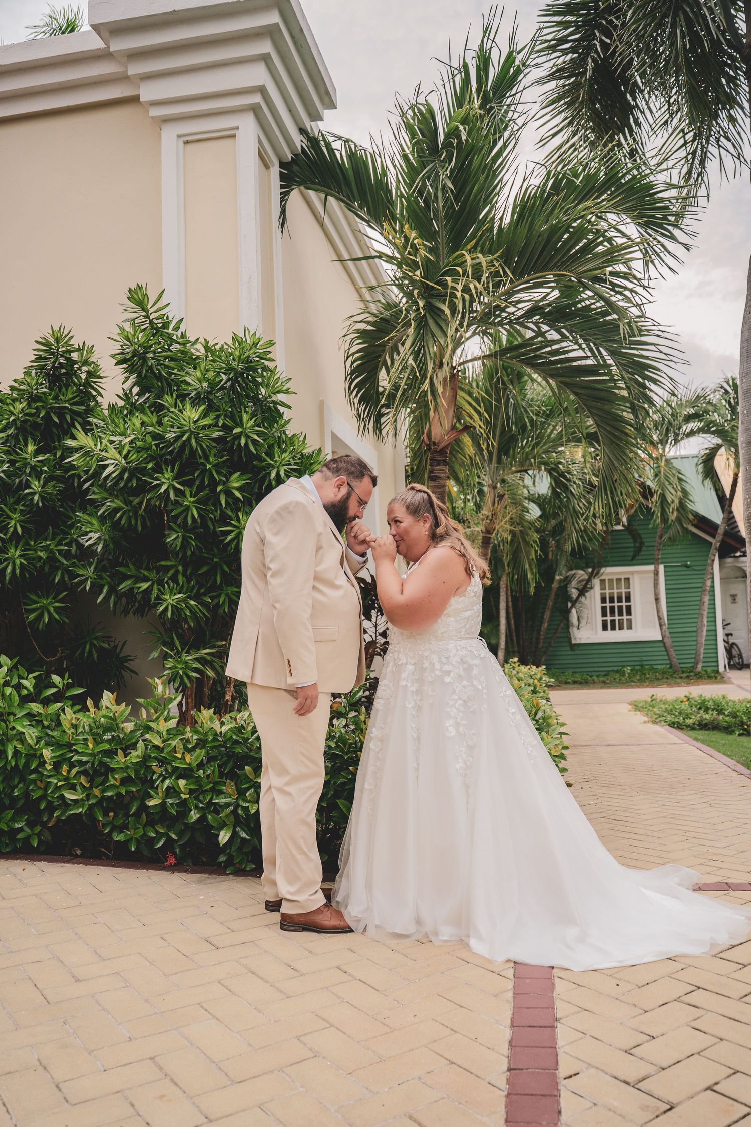 Bride and groom sharing an intimate moment on a brick path with tropical palms.