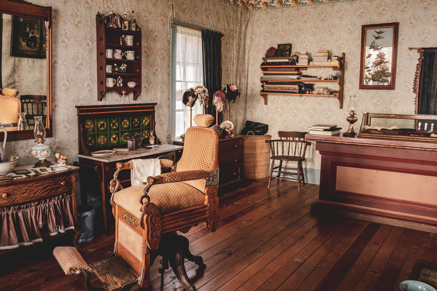 Vintage Victorian-style room with ornate wooden furniture, patterned wallpaper, and hardwood floors.