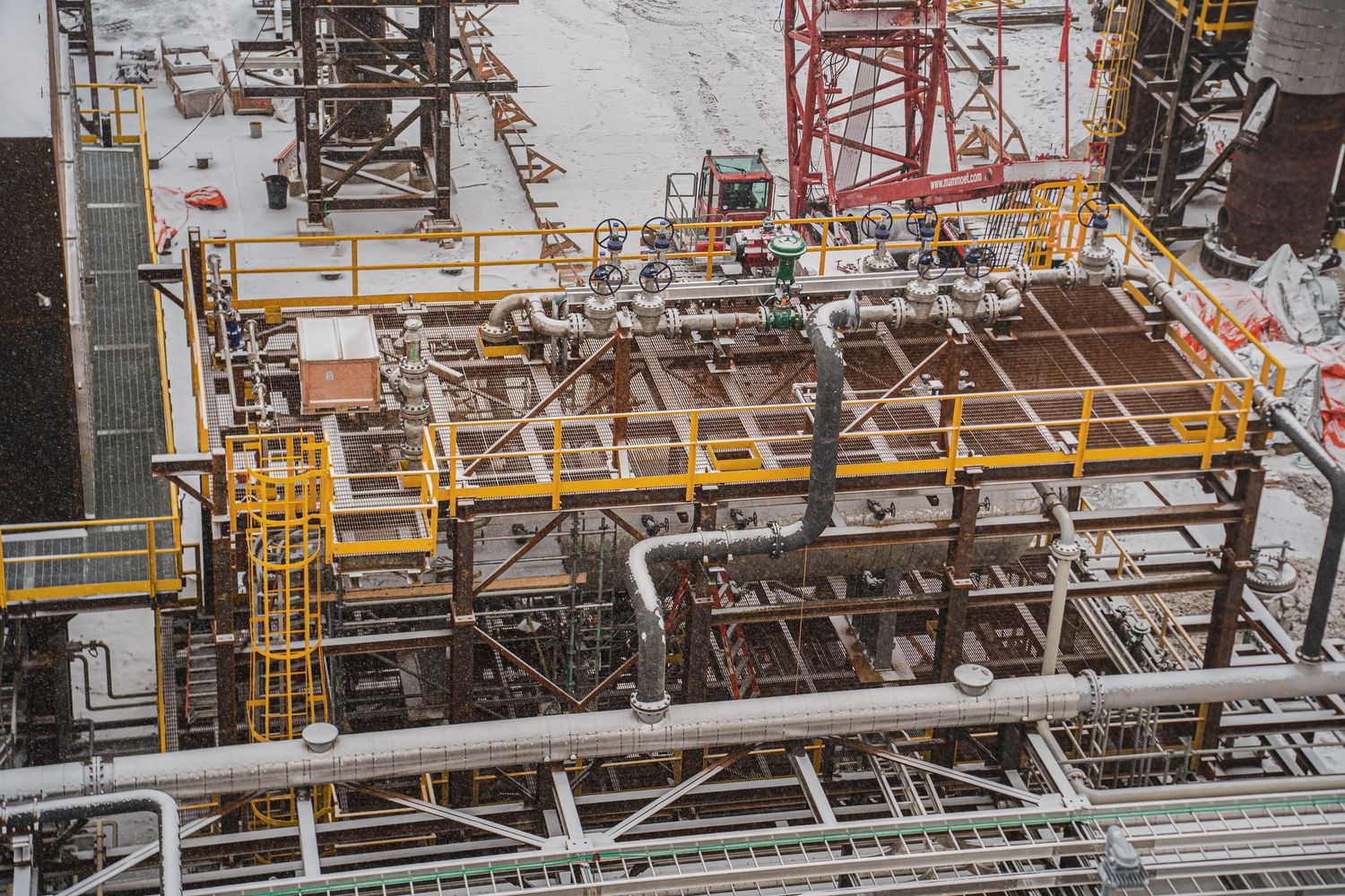 Aerial view of an industrial oil and gas processing facility with yellow safety railings.