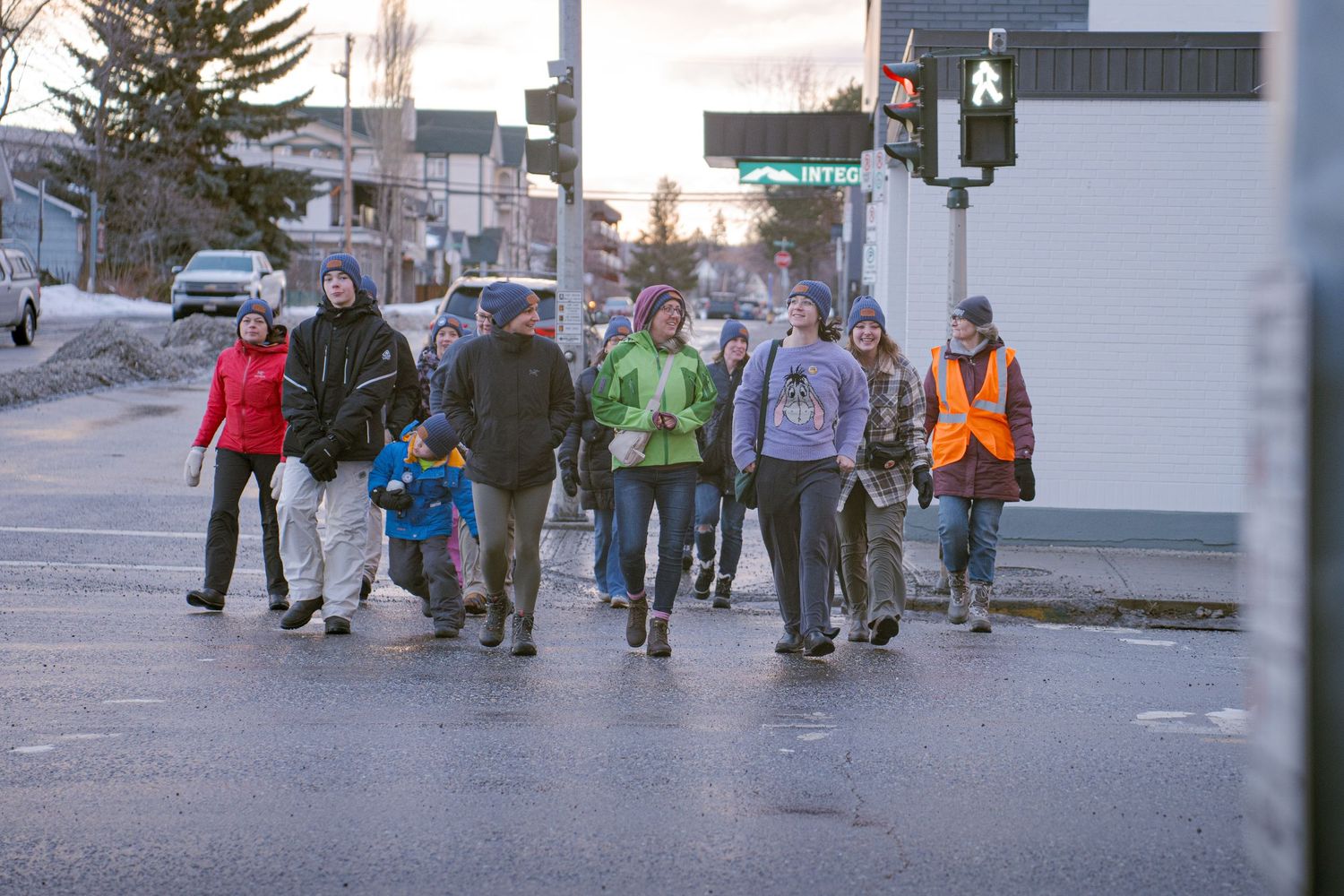 A group of people crossing a wet street intersection together on a cold winter day at coldest day of the year, AWAC event.