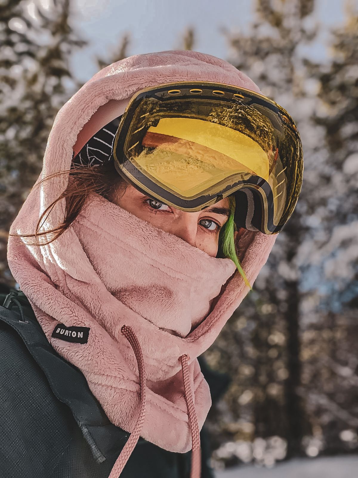 Portrait photoshoot of a Woman wearing pink fleece balaclava and yellow lens ski goggles in snowy mountain setting in Quesnel BC