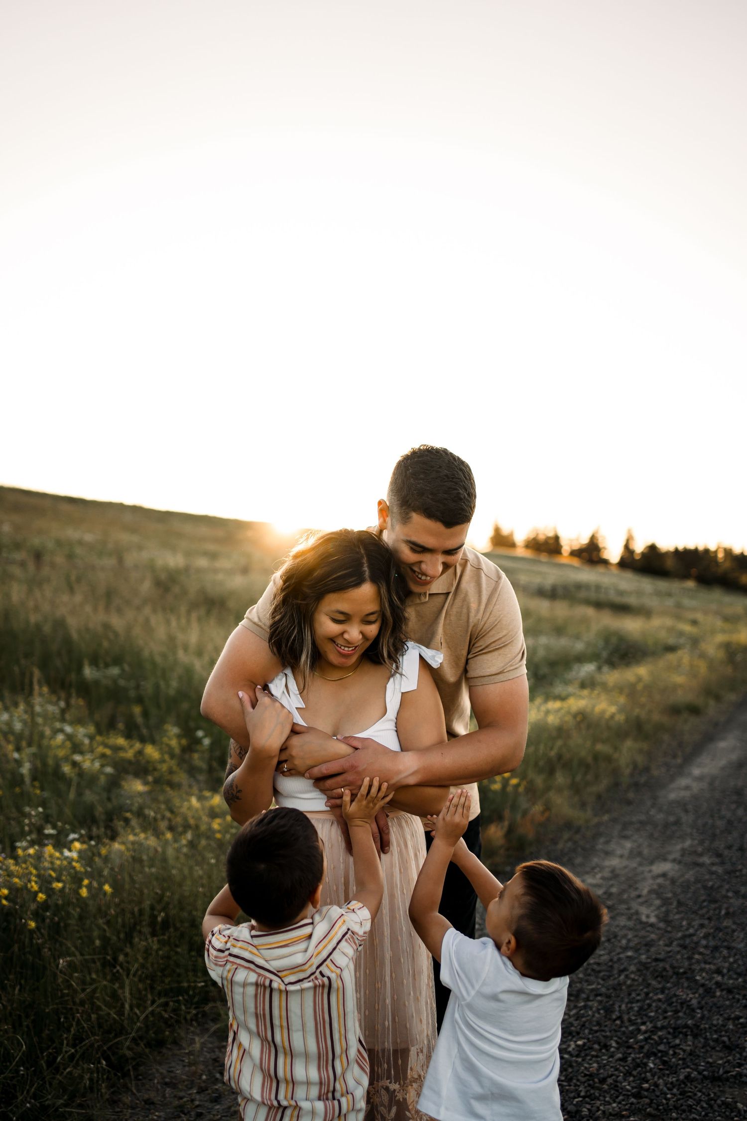 Family sharing playful moments together on a country path at sunset.
