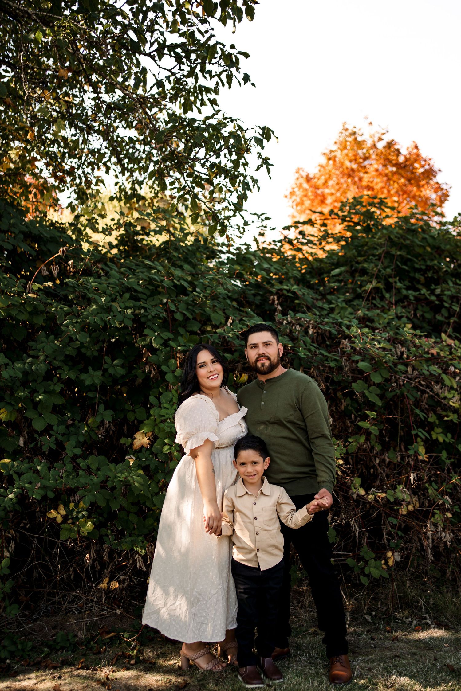 Family portrait session against autumn foliage at sunset.
