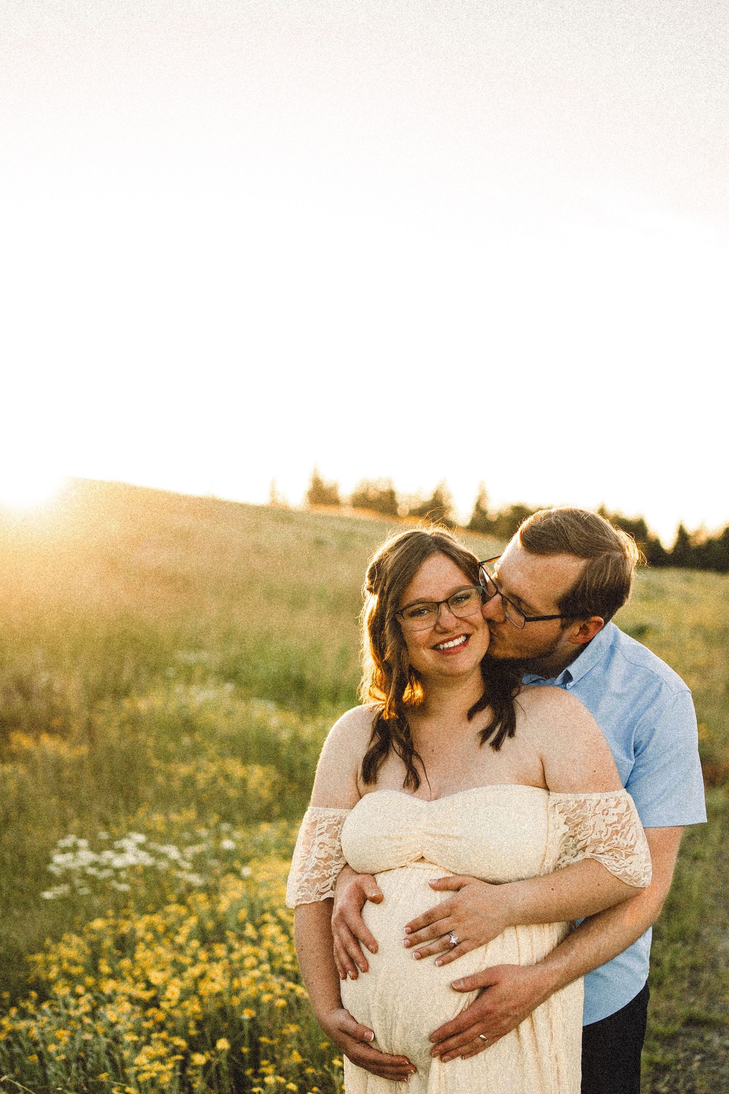 Intimate maternity photos captured in a golden meadow at sunset.
