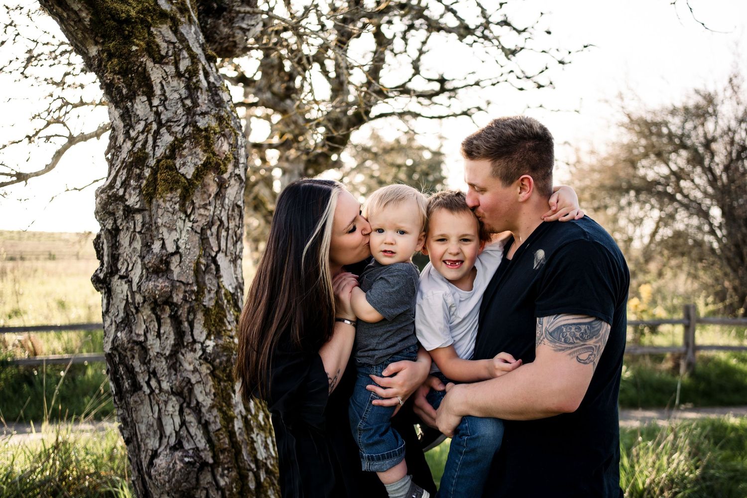 Family sharing tender moments together under a large tree.