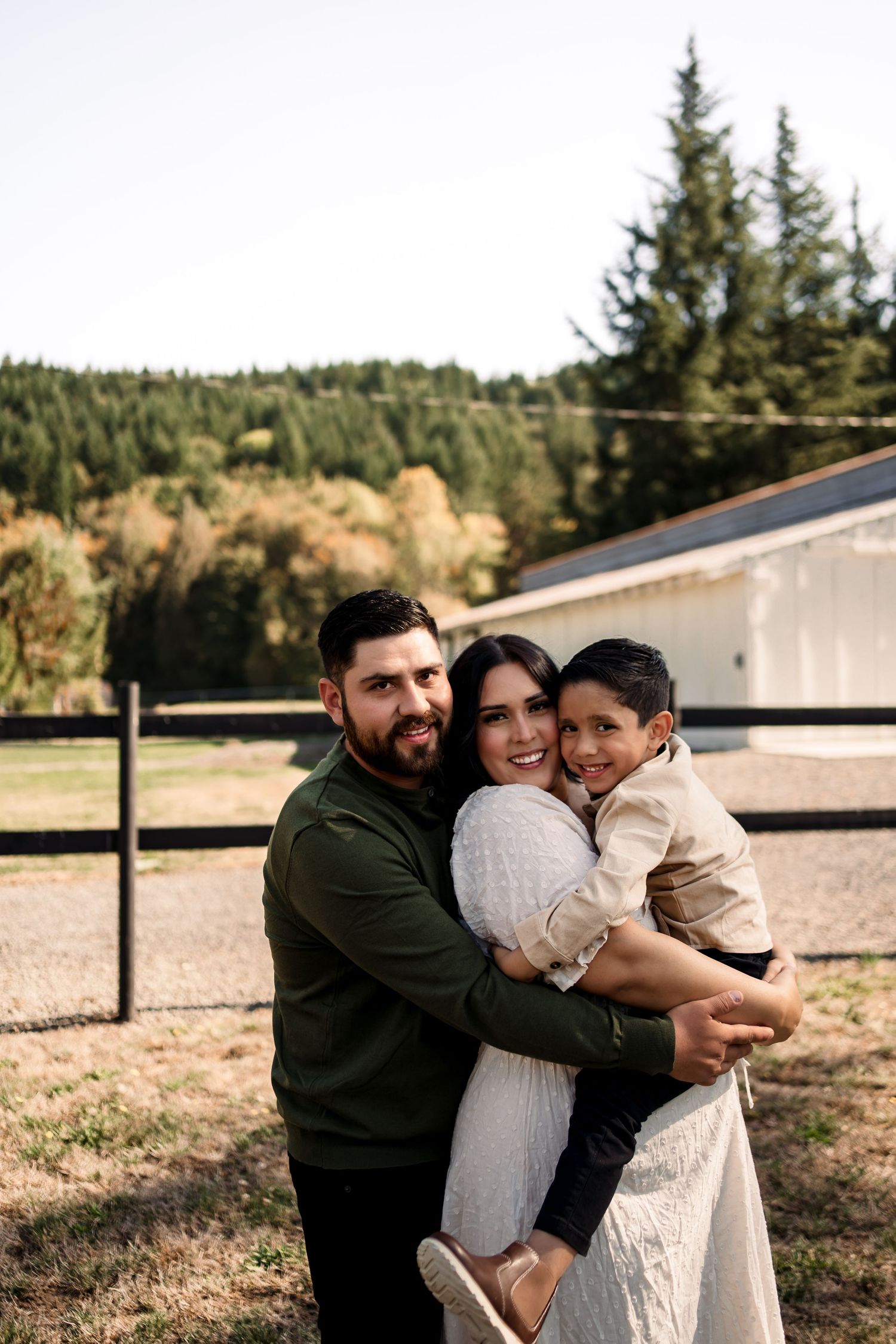 Family embracing in warm group hug outdoors during golden hour.