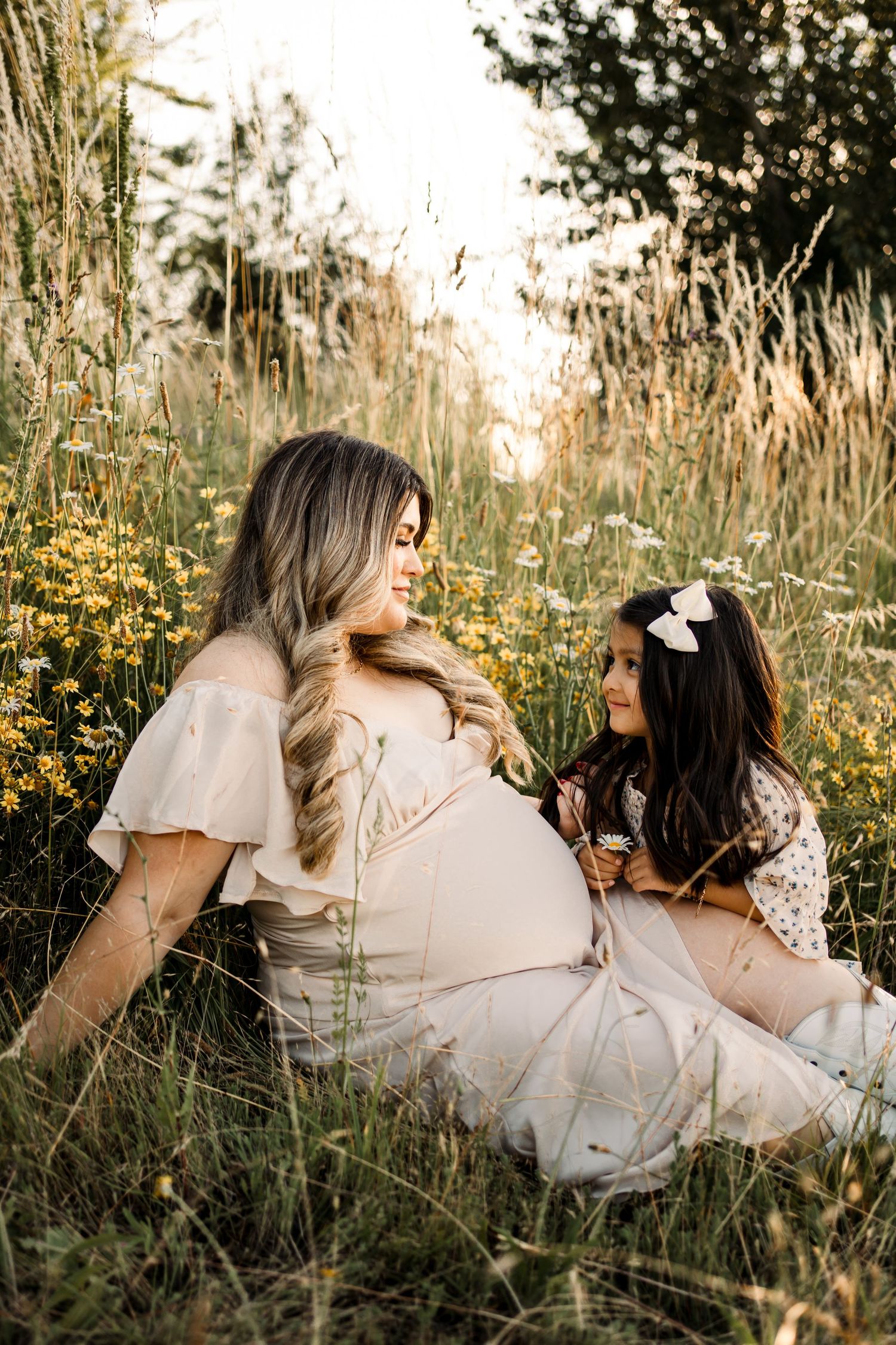 Family lying in tall grass during sunset photography session.