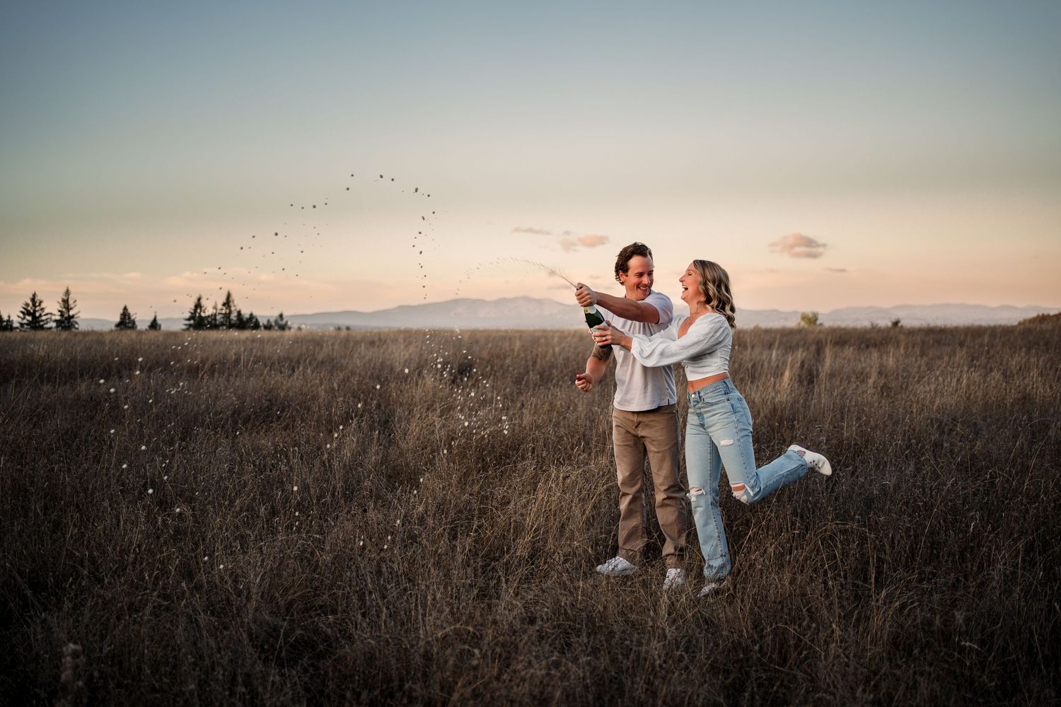 Couple dancing in an open field during golden hour sunset.