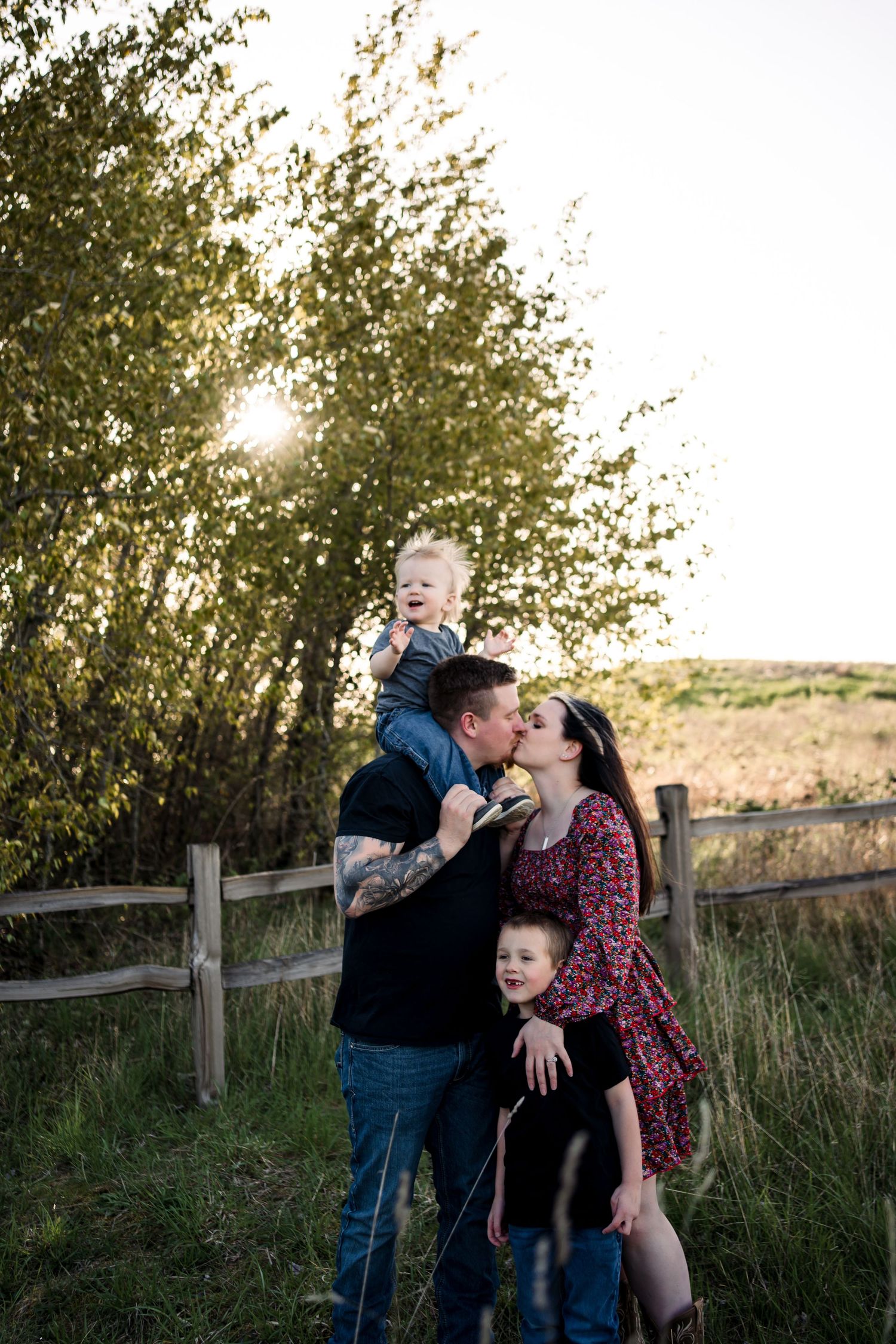 Family sharing intimate moments together by a rustic fence during sunset.