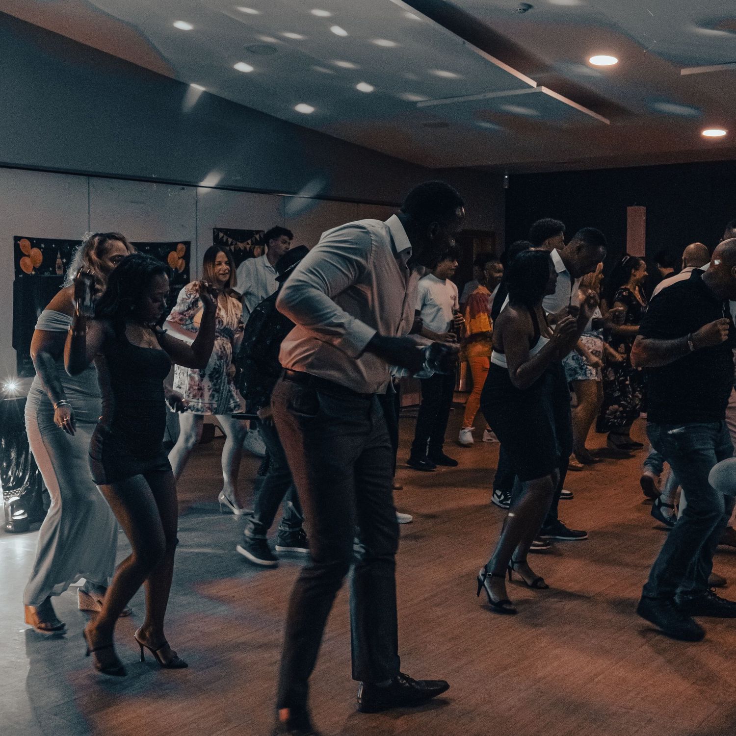 Couples dancing together in a dimly lit studio space during what appears to be a group dance class.