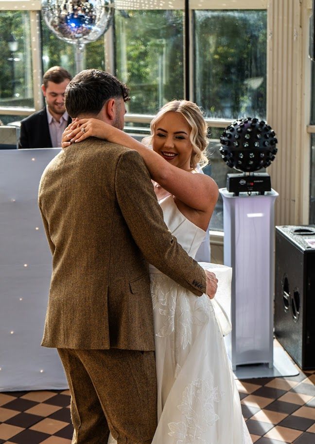 A couple shares a romantic dance on a black and white checkered floor at their wedding reception.