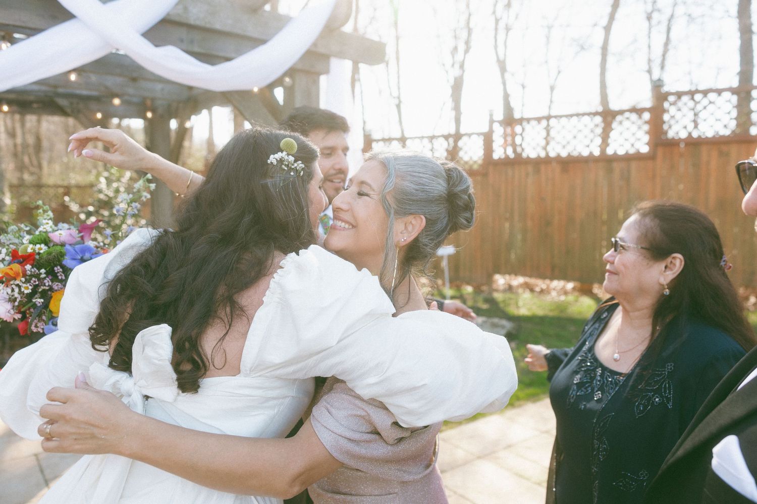 Bride sharing a warm hug with family members following an outdoor garden wedding ceremony.