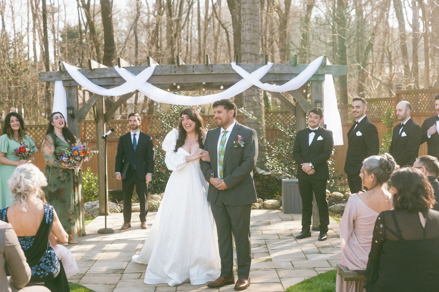Bride and groom sharing their first dance at an outdoor wedding ceremony with floral arch backdrop.