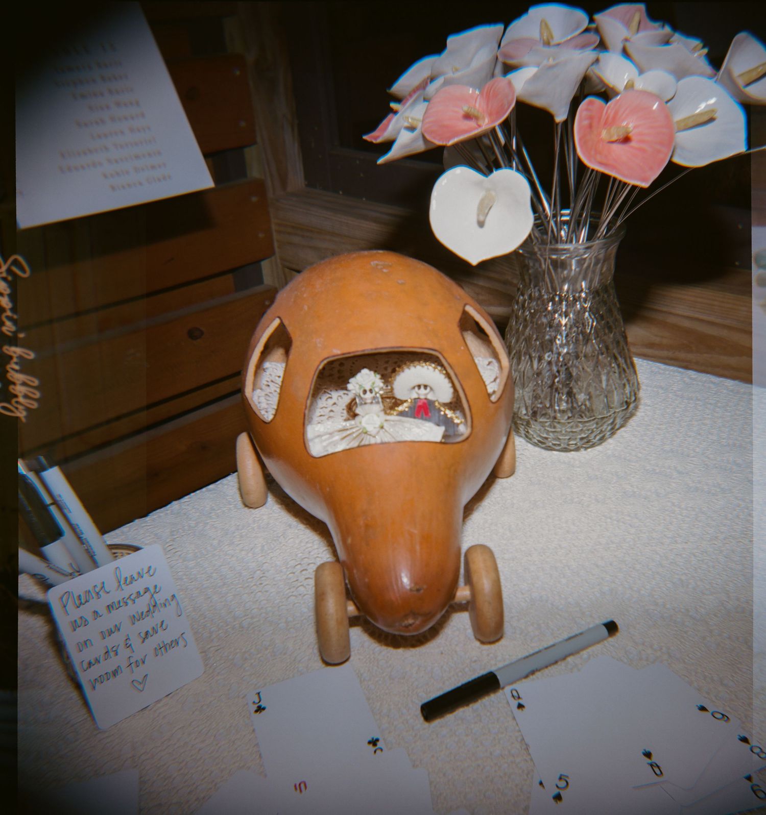 Wooden toy airplane on a table with a crystal vase of pink flowers and cards at a baby shower.