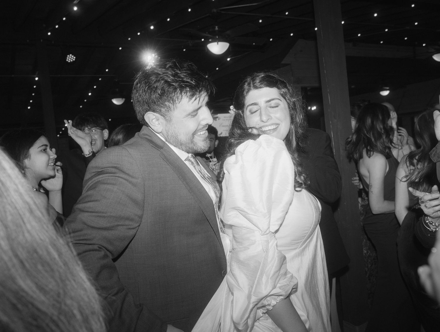 Couple dancing joyfully at a wedding reception in black and white photography.