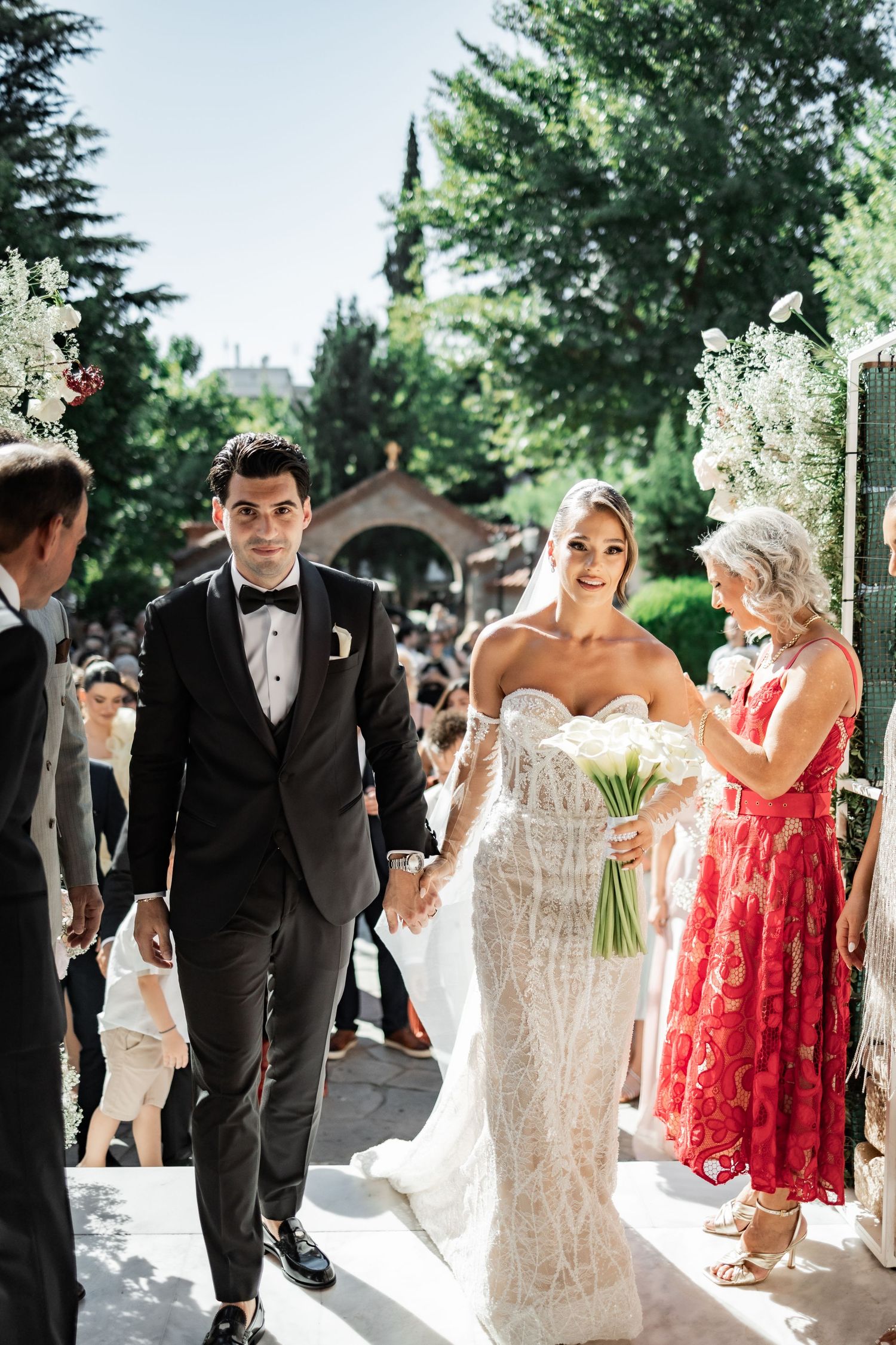 Bride and groom walk down the aisle hand in hand at an outdoor wedding ceremony surrounded by guests.