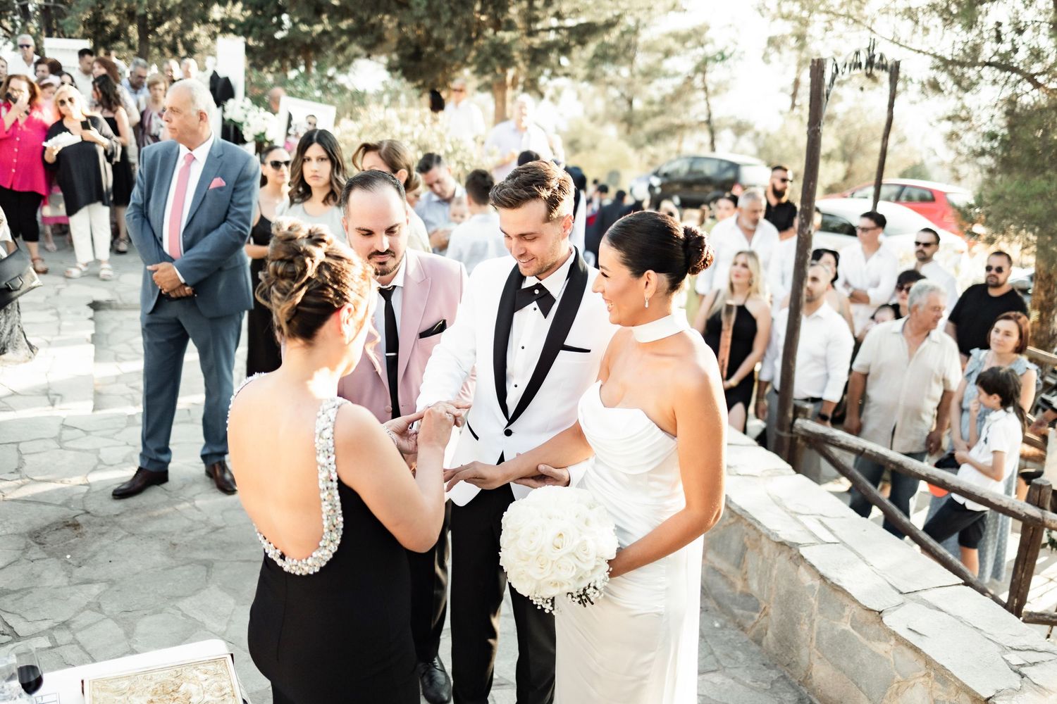 Wedding guests celebrate during an outdoor reception with natural scenery.