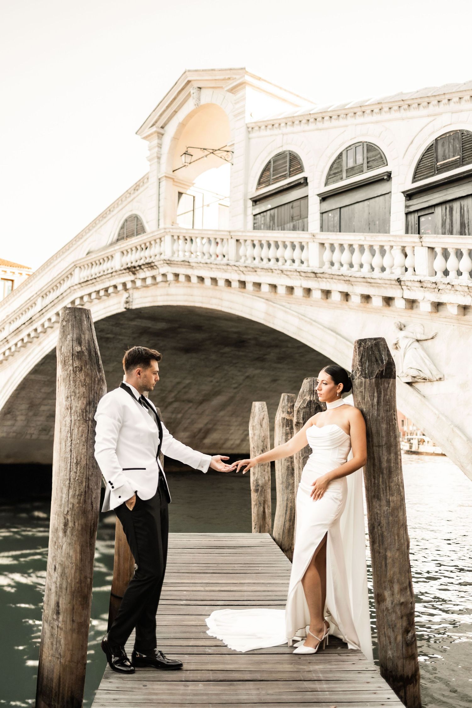 Playful poses on a wooden dock beneath the historic Rialto Bridge in Venice.