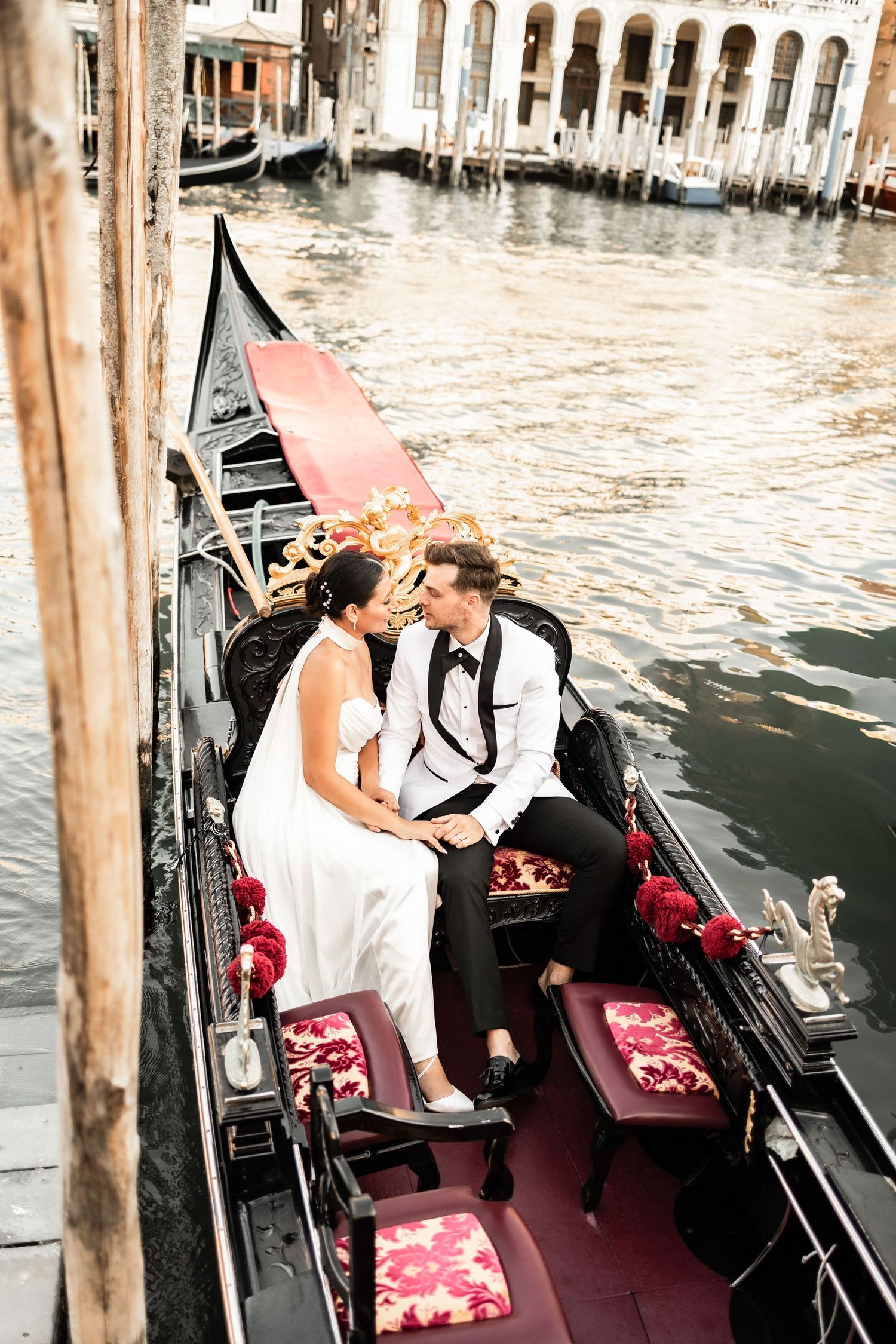 Newlyweds share an intimate moment in a traditional Venetian gondola with red velvet seats.