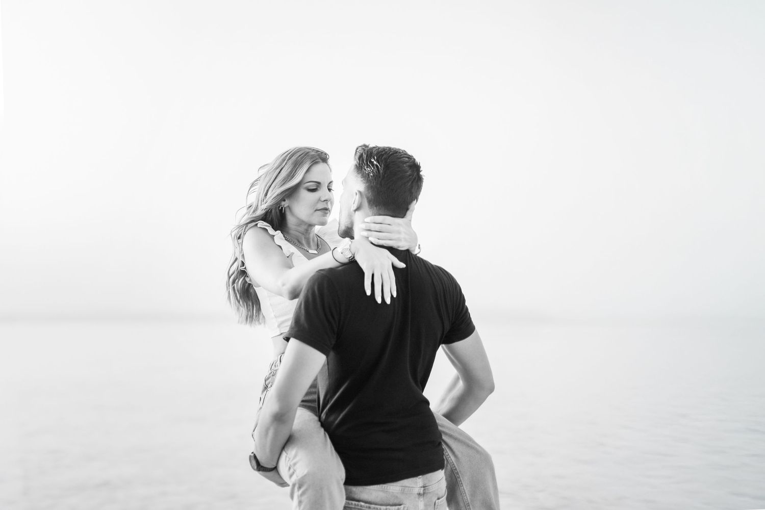 A couple walking together on a beach during sunset, holding hands and embracing in silhouette.