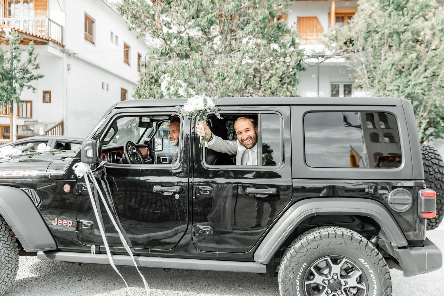 Line of black vehicles parked outside a wedding venue with decorative ribbons.