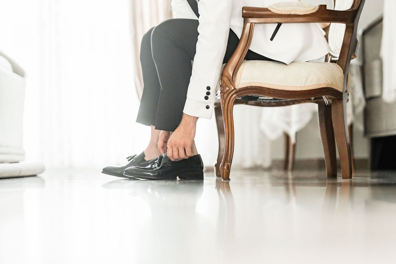 Detail shots of formal footwear and attire near an elegant wooden chair.