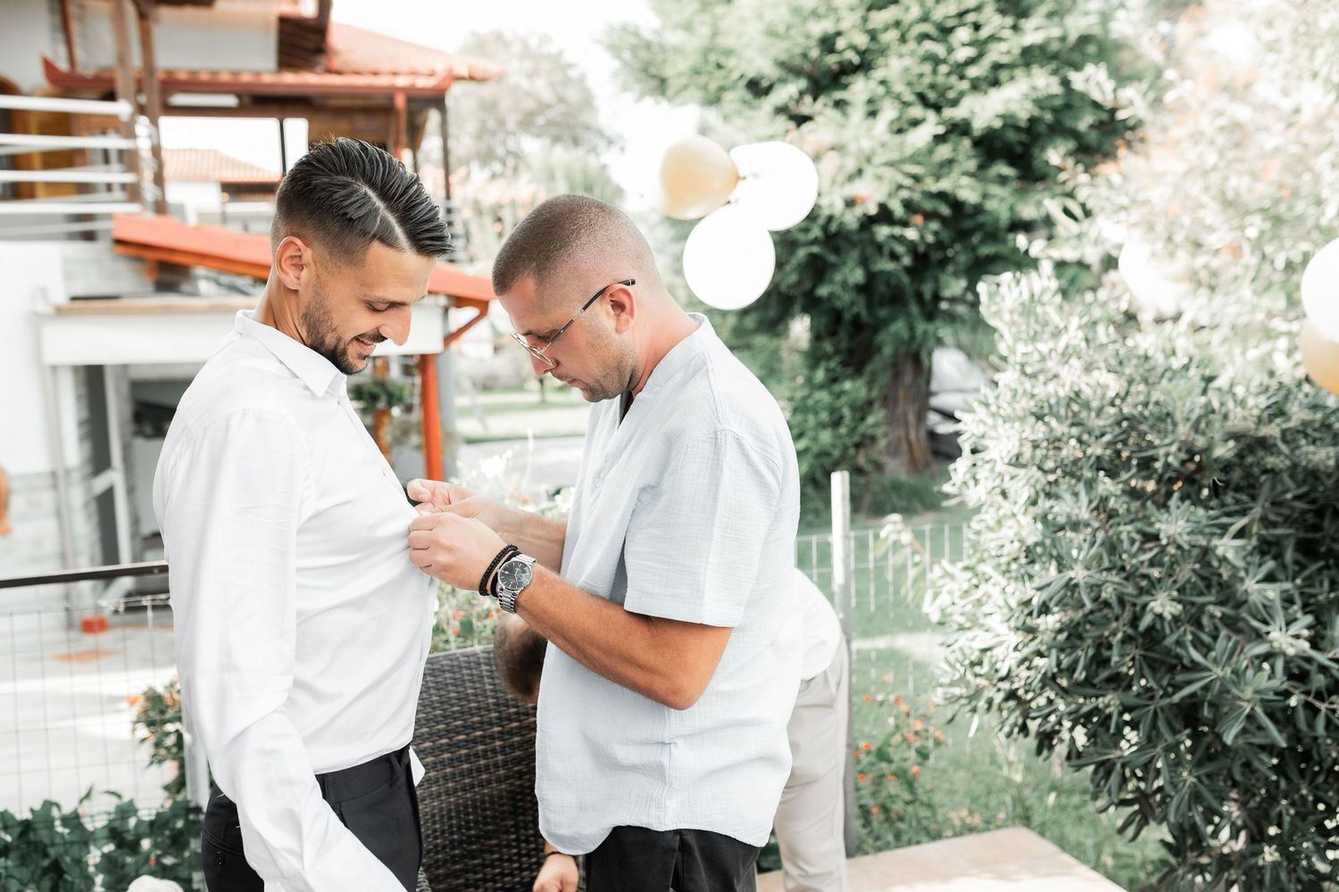 People in white shirts gather outdoors for a wedding celebration.