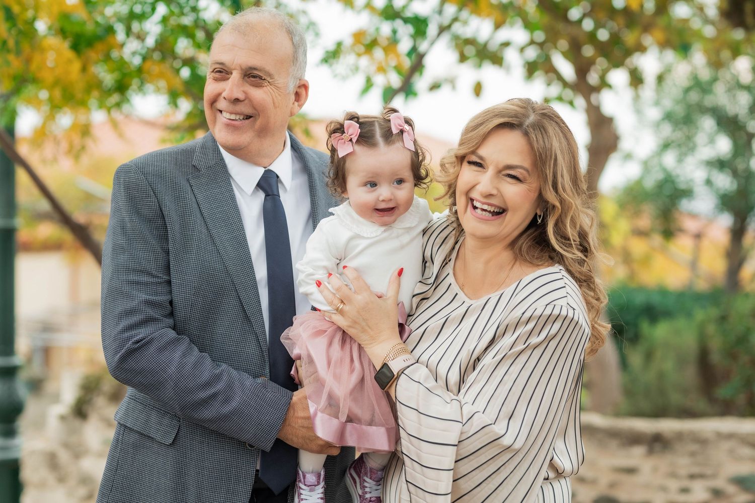 Family members share joyful laughter while posing together against a backdrop of fall foliage.