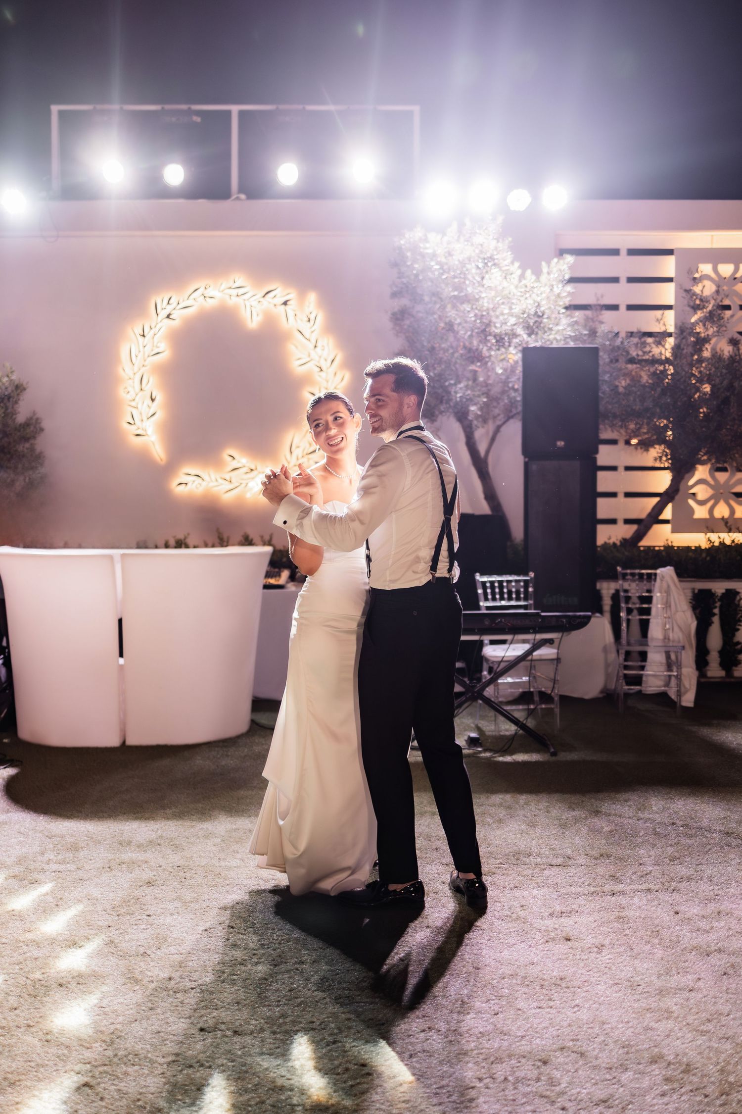 First dance at wedding reception with illuminated decorative wreaths creating romantic ambiance.