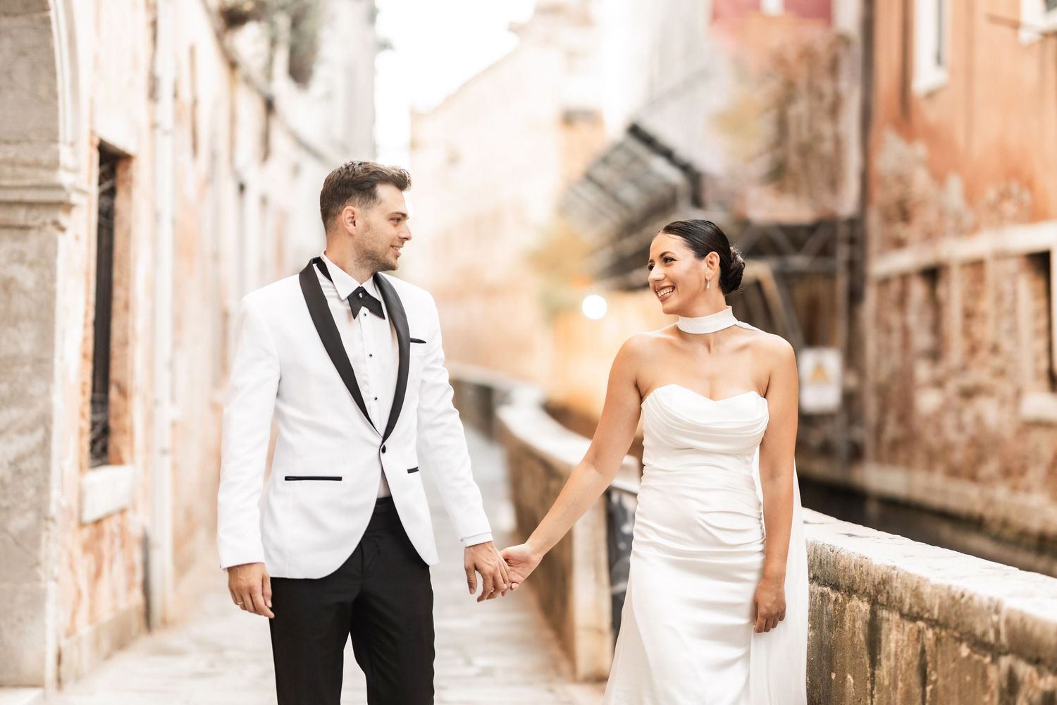 Romantic couple poses along Venice's iconic canals with historic architecture in the background.