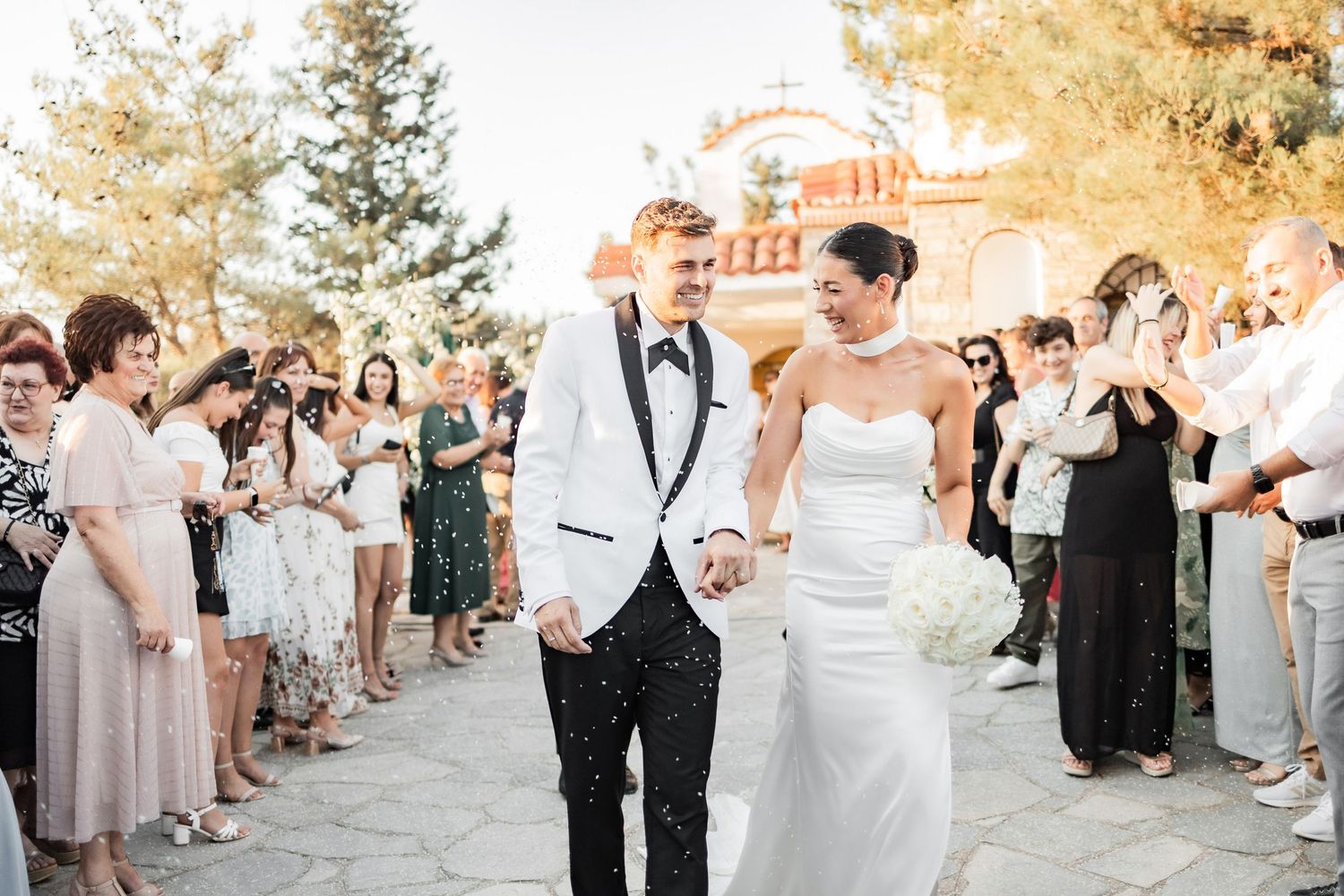 Wedding party and guests gather on a scenic outdoor path during golden hour celebrations.