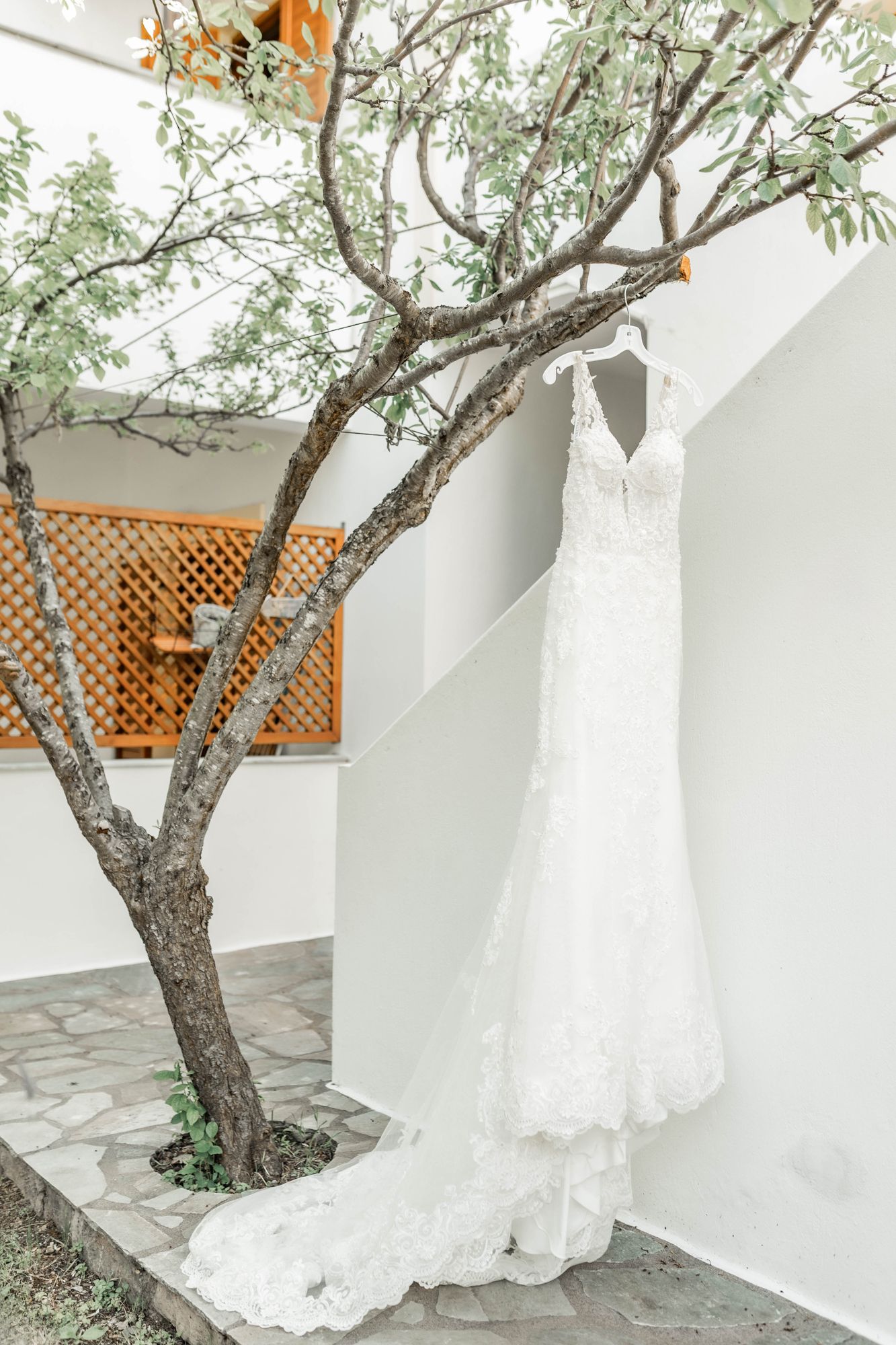 Multiple views of an elegant white wedding dress displayed against a Mediterranean-style white wall.