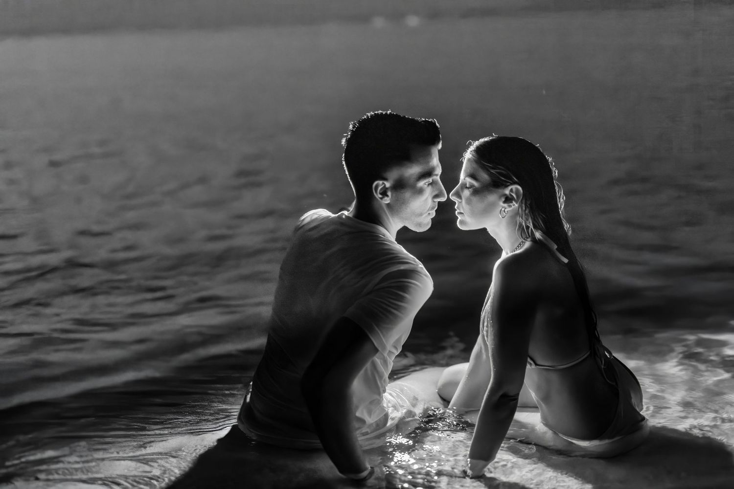 A black and white photo sequence showing two people in silhouette kissing at sunset by the water.
